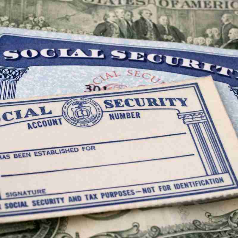 Two Social Security cards, one older and one newer, resting on a background of US currency. The image symbolizes the financial and administrative aspects of Social Security Disability and Medicaid benefits.